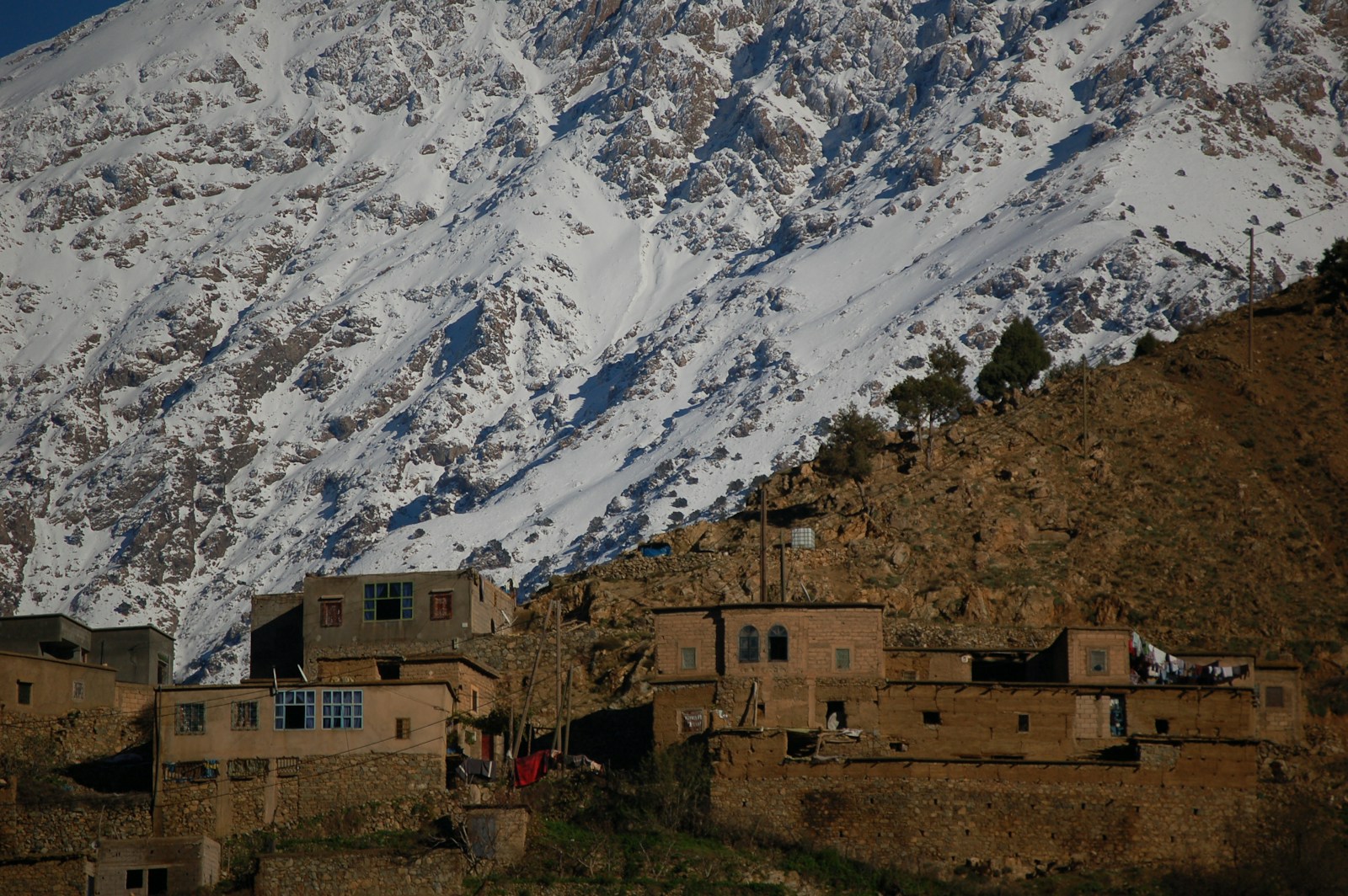 brown concrete building near snow covered mountain during daytime